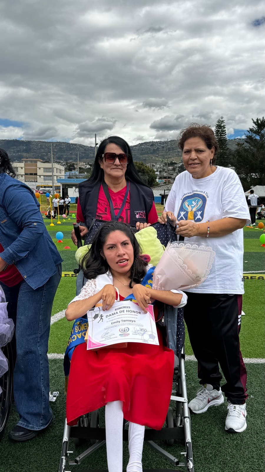 Entrega de un reconocimiento a una beneficiaria en silla de ruedas durante Atletismo Sin Límites